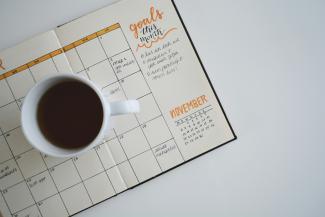 white ceramic mug with coffee on top of a planner by Estée Janssens courtesy of Unsplash.